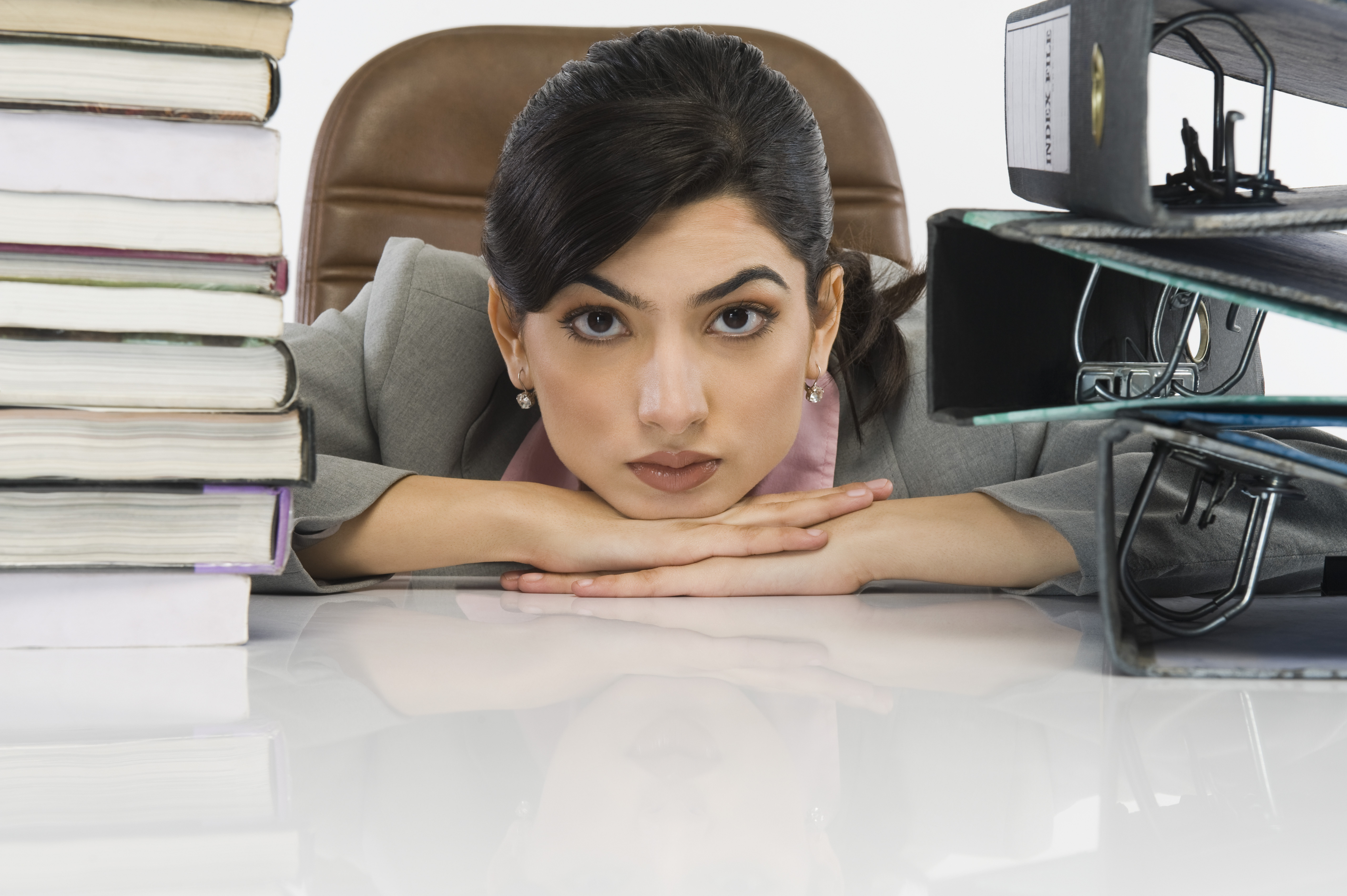 Stack of books and binders in front of a businesswoman at desk