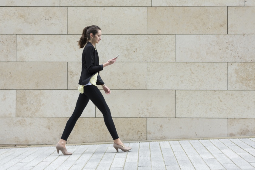 Businesswoman looking at phone while walking.